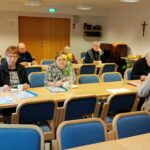 Pöydissä istumassa ihmisiä.